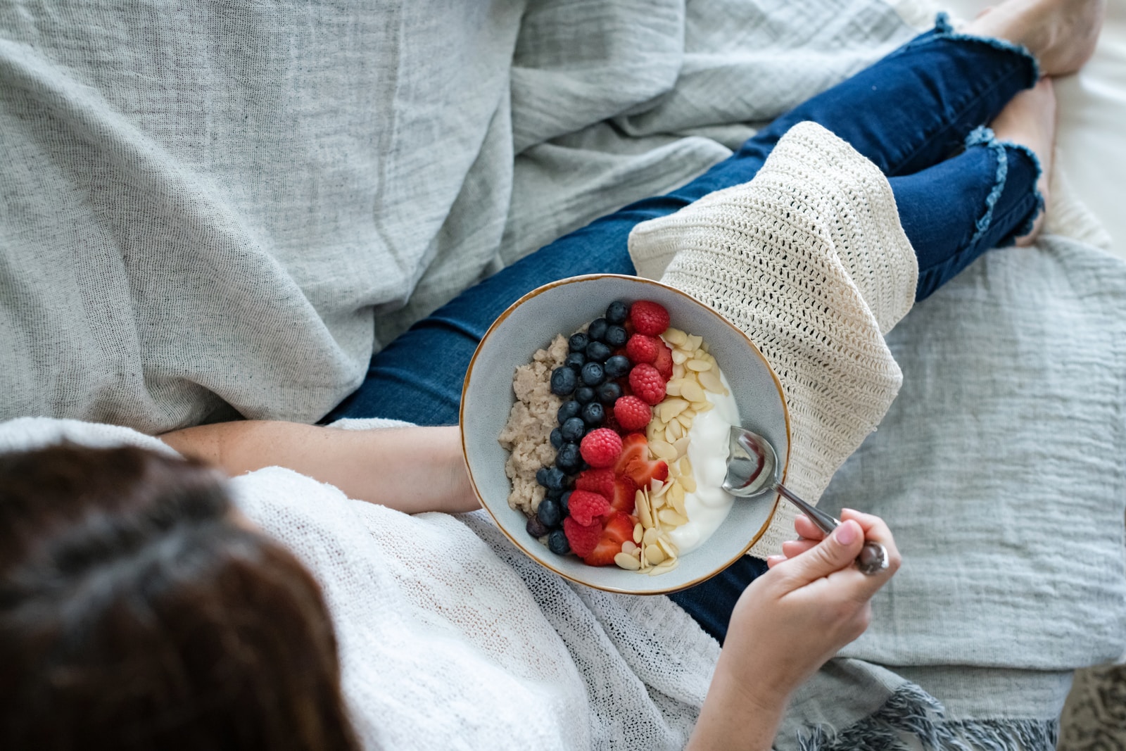 person holding white ceramic bowl with red and blue berries