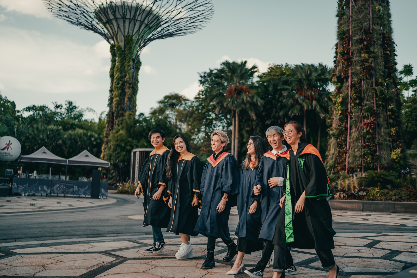 group of people in black academic dress standing on gray concrete pavement during daytime
